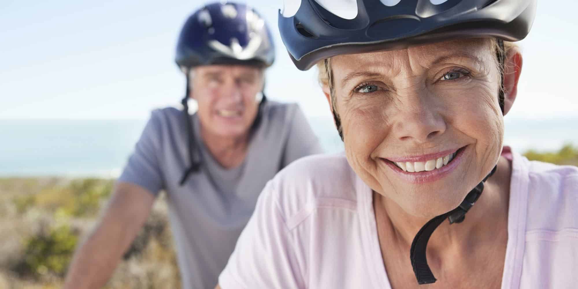 Denago Portrait of mature woman in sports helmet smiling with man in background